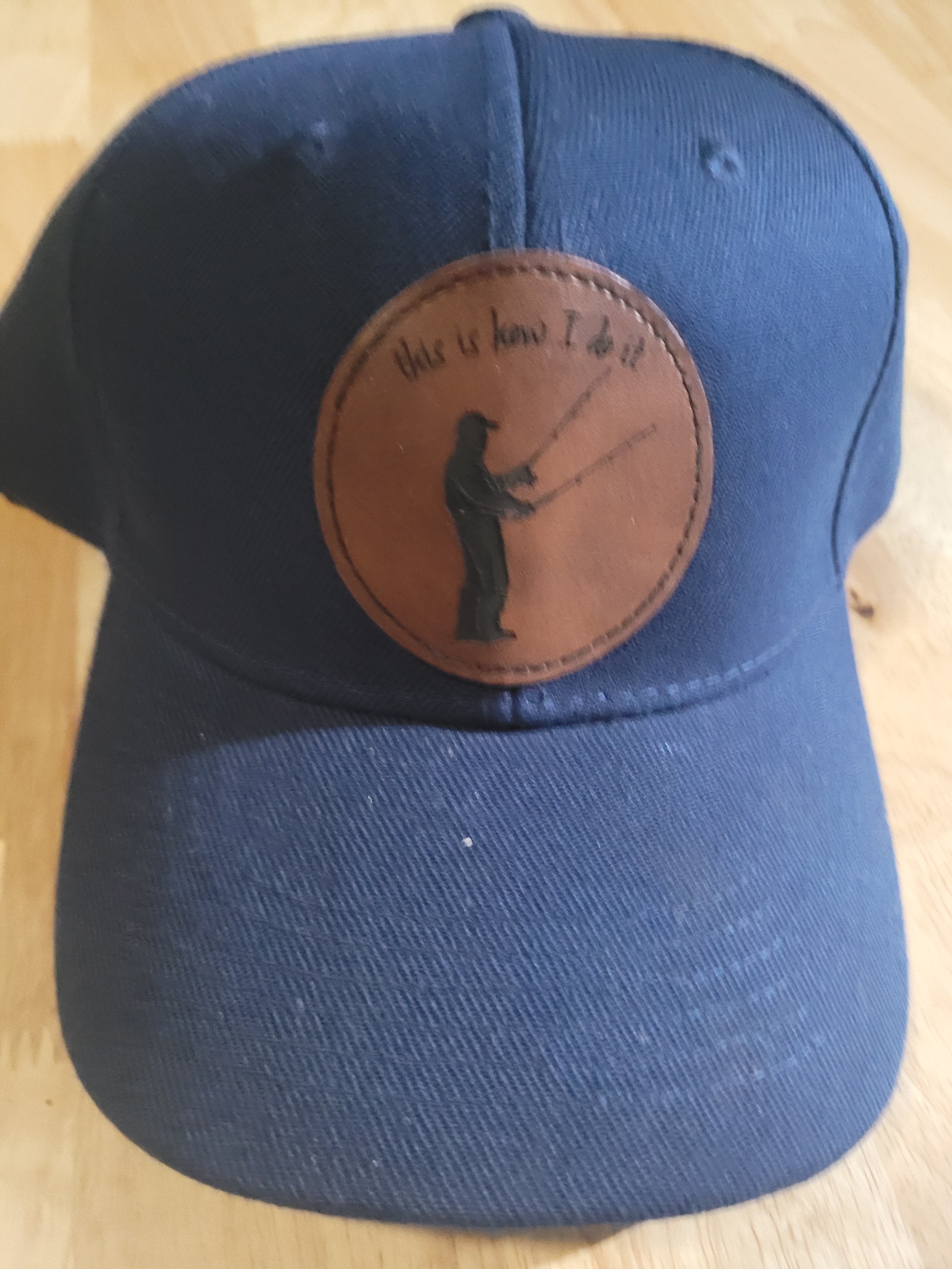 Blue Ball Cap with Patch of a Fisherman with two rods in his hands "This is How I do it"