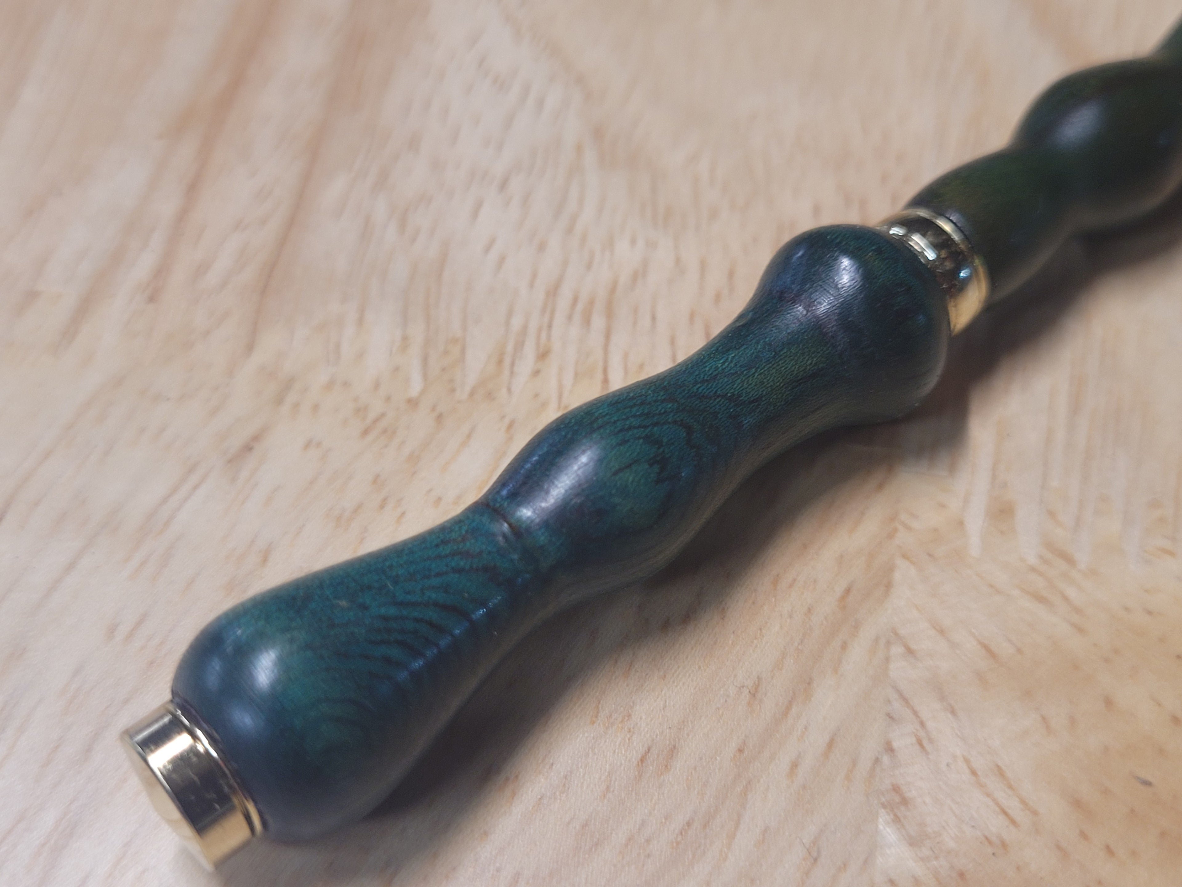 Green wooden handle with gold accents on a wooden surface